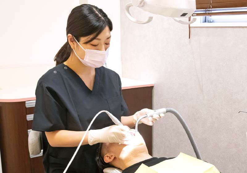 女性の歯科衛生士が患者の口腔状況を確認している。