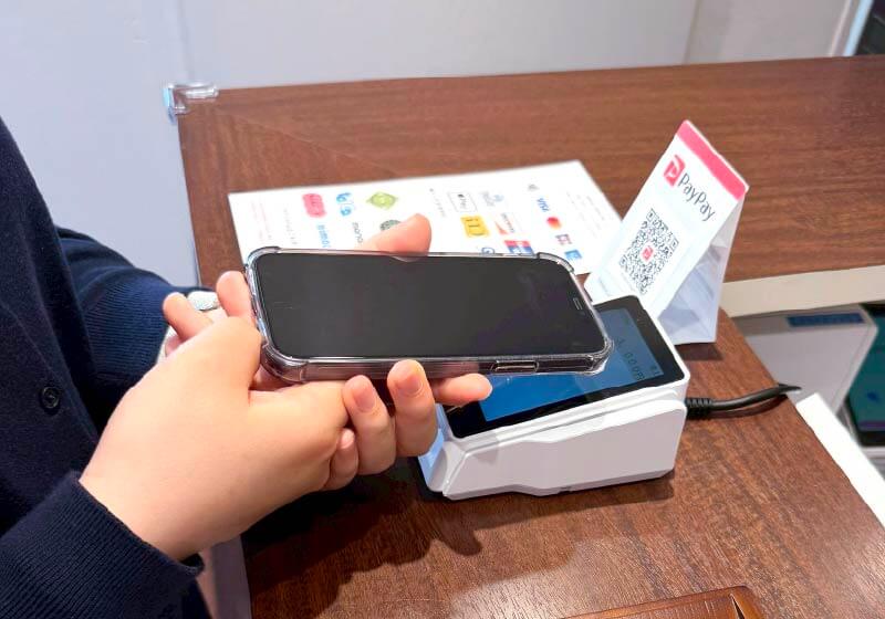 スマートフォンを電子決済機にかざしている。