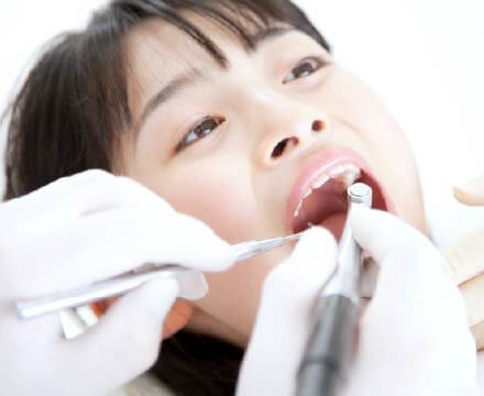 女の子が口を開いて歯の治療を受けている。