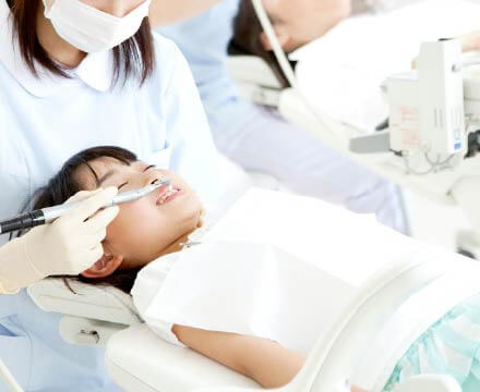 女の子が診察台で歯のクリーニングを受けている。